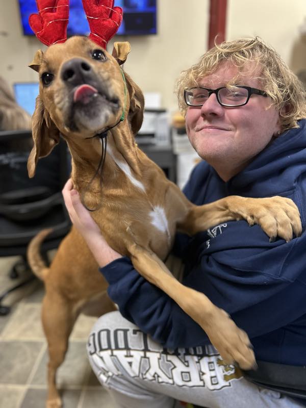 A member of the team holding a dog that is licking their face